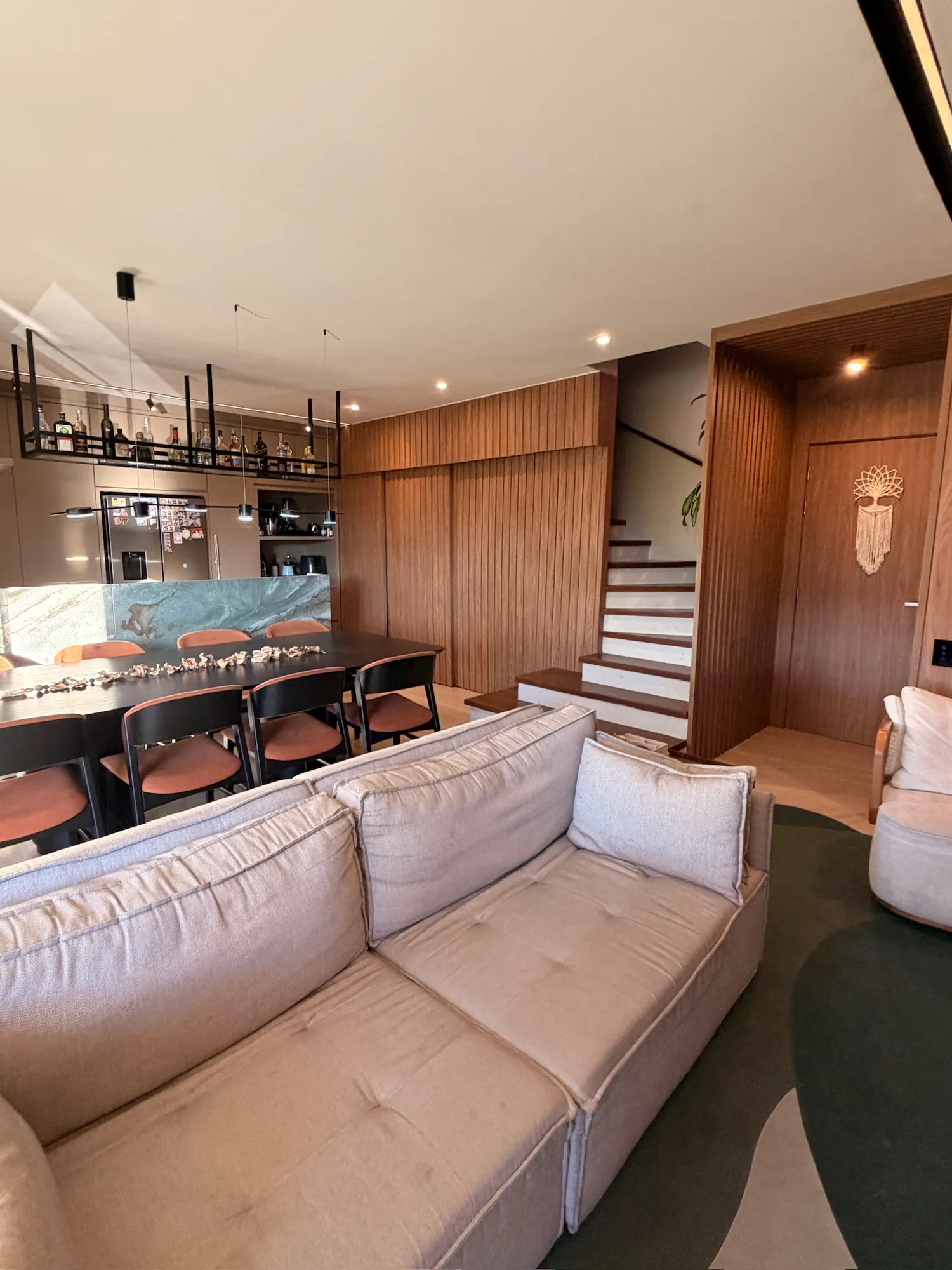 Living integrado do duplex com marcenaria em madeira e iluminação em tons quentes
